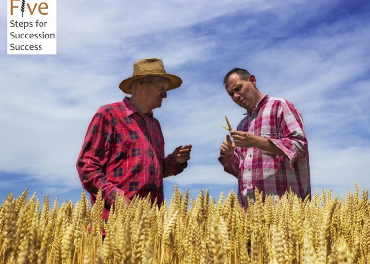 Two farmers talking in wheat field in front of combine harvester